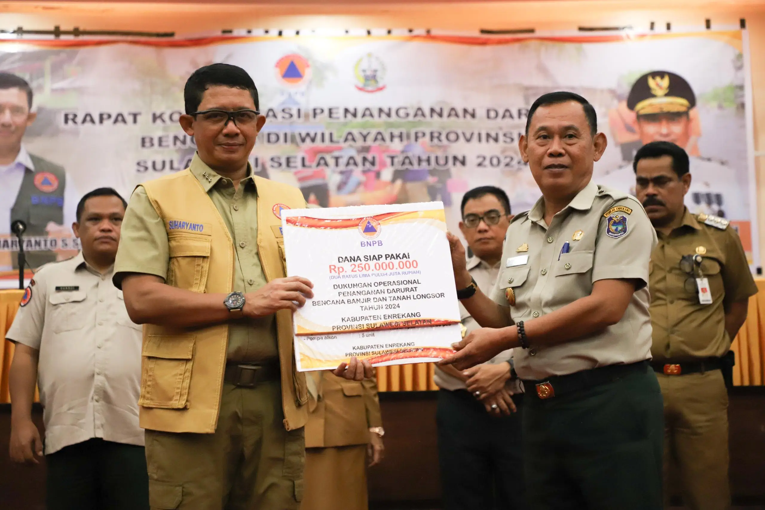 Kepala BNPB Letjen TNI Suharyanto S.Sos., M.M (kiri) memberikan bantuan secara simbolis kepada perwakilan Pemerintah Kabupaten Enrekang untuk percepatan penanganan banjir dan tanah longsor, Senin (6/5).